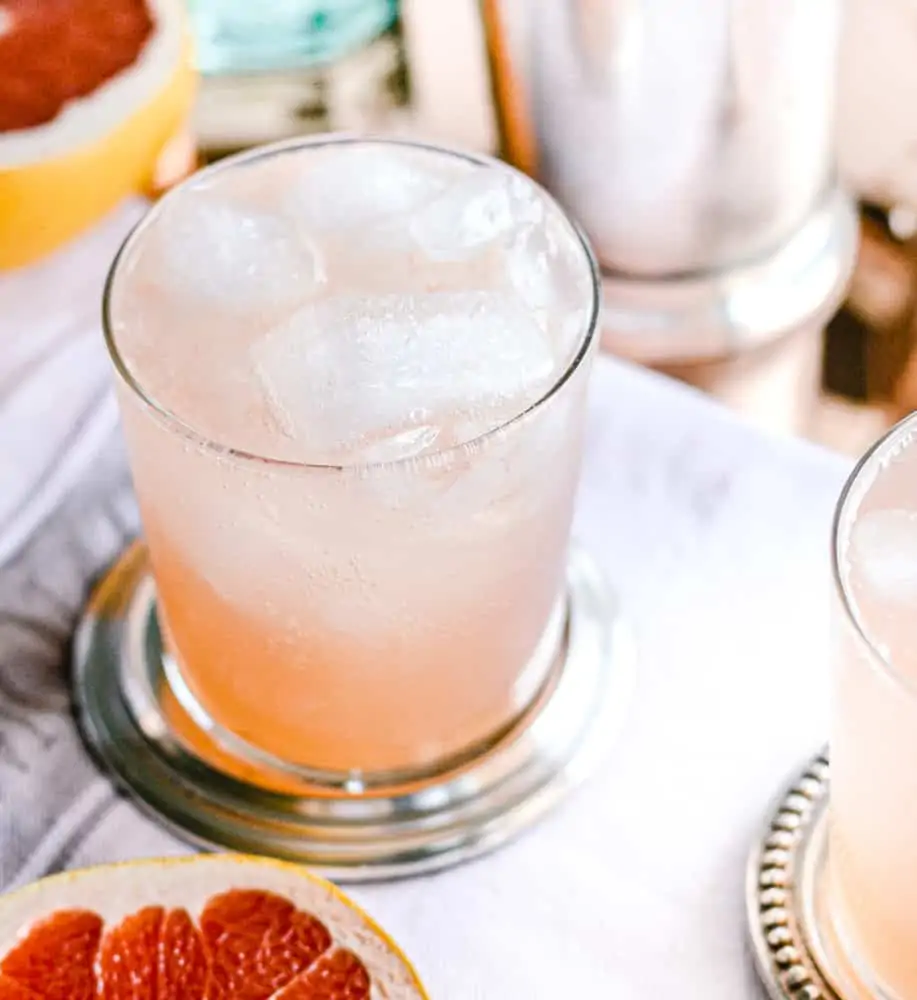 Grapefruit Collins Cocktail with Rosemary Simple Syrup on silver coaster.