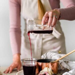 Homemade Elderberry Syrup being poured into jar for colds and flus.