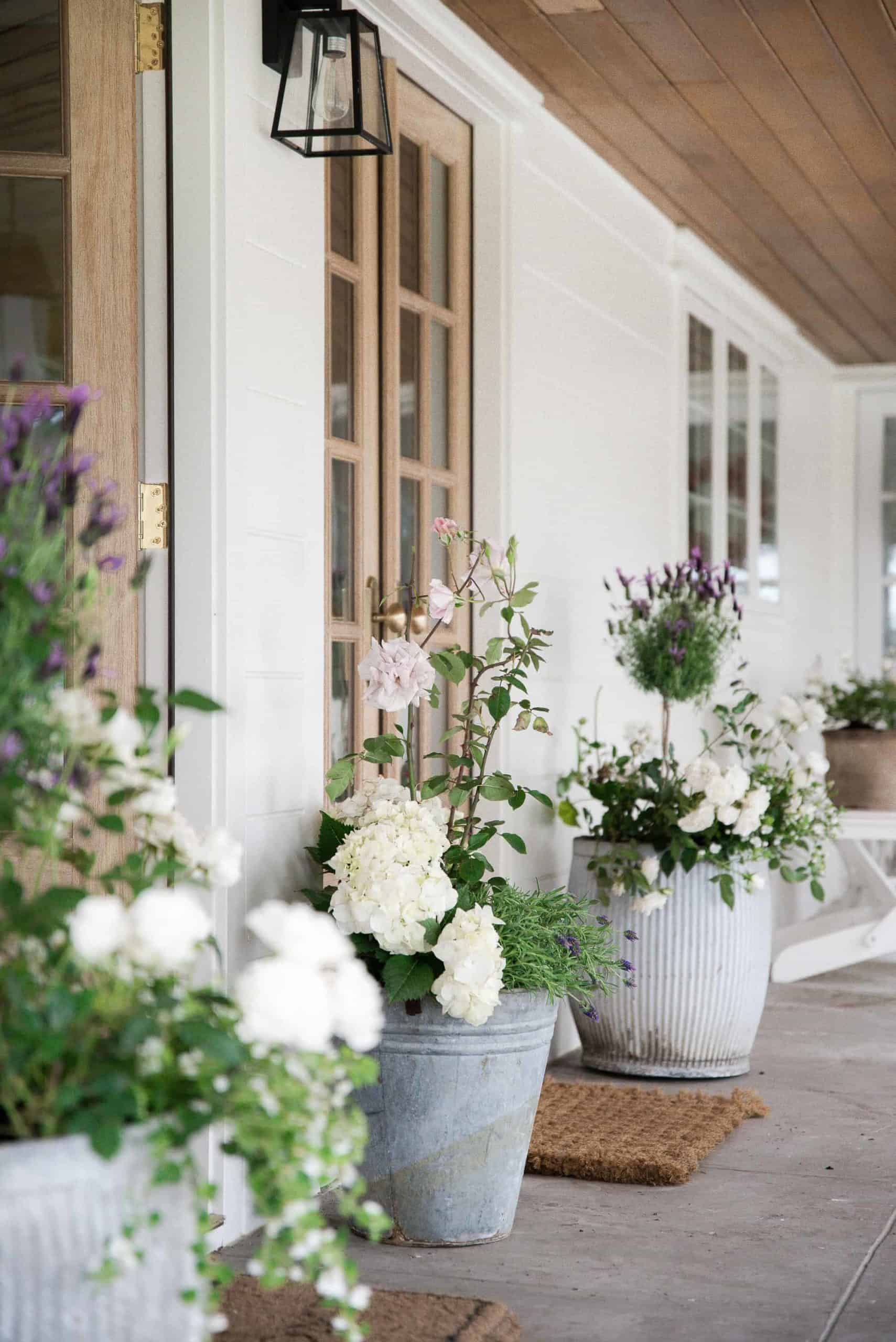 Gorgeous flower pots on a farmhouse porch with white flowers and lavender. 