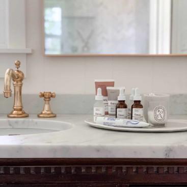 Skincare products on white bathroom counter top next to sink