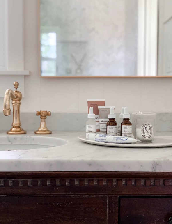 Skincare products on white bathroom counter top next to sink