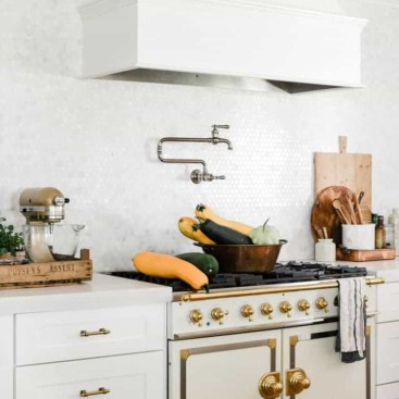 White modern farmhouse kitchen with french oven range pictured with squash on top of stove