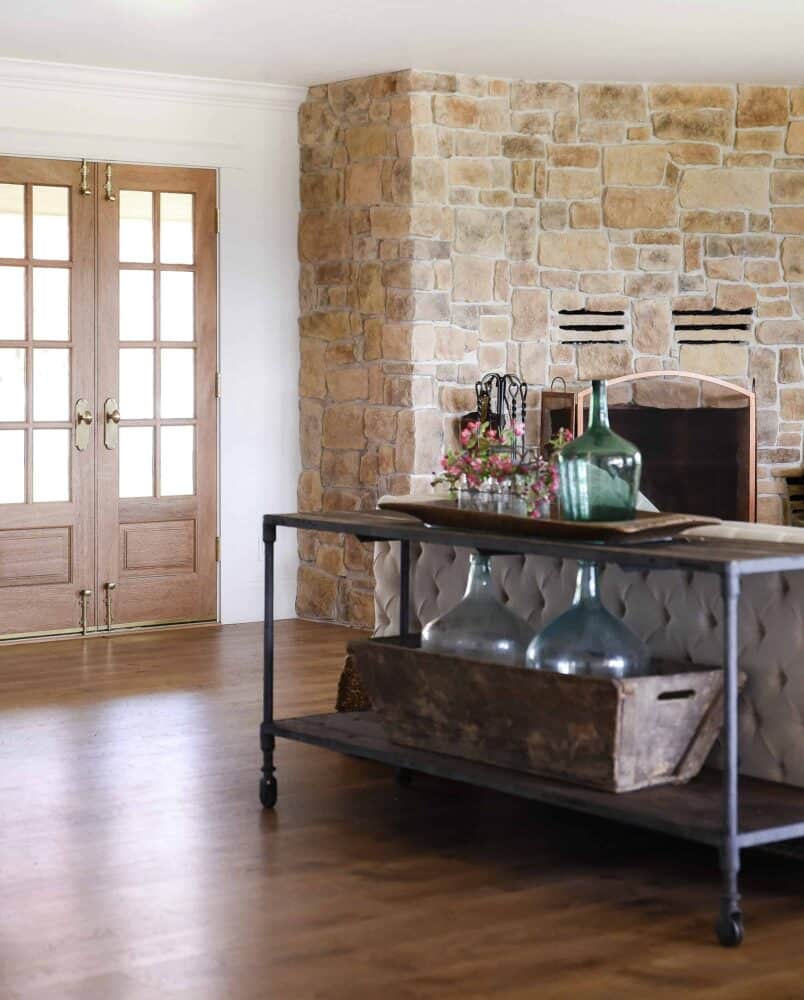 Living Room Decor with Vintage Demijohns and Wood French Doors with Stone Fireplace in Background