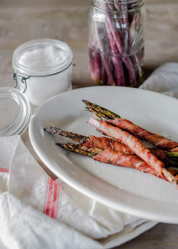 Looking for an easy, delicious, and healthy side dish this summer (or winter for that matter)? Try this paleo bacon wrapped asparagus cooked in your oven or on the BBQ in under fifteen minutes! Crispy and salty, your whole family will love these!