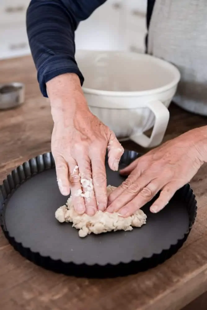 Woman pressing dough into tart pan