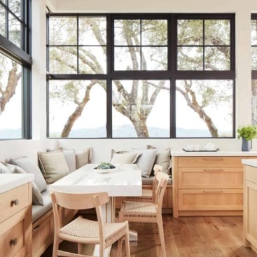 Kitchen banquette with wood chairs and black frame windows