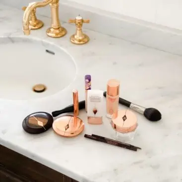 Makeup on marble countertop with brass faucet