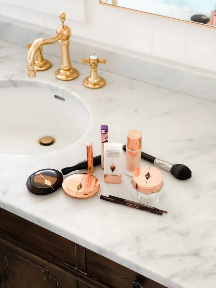 Makeup on marble countertop with brass faucet