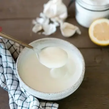 Bowl of garlic greek yogurt sauce on wood table