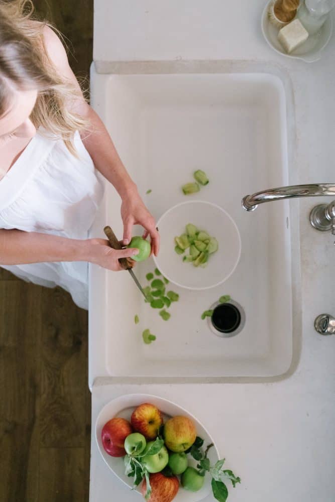 Girl peeling apples in farm sink