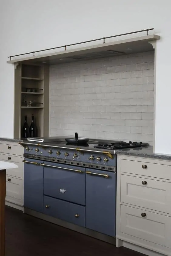 Taupe cabinets next to a navy blue range with beige tile