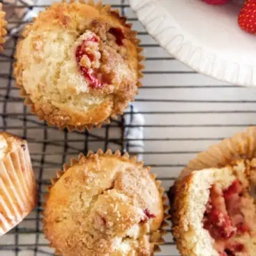 Strawberry Muffins on cooling rack with a bowl of strawberries