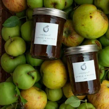 Apple preserves in mason jar in front of basket of apples