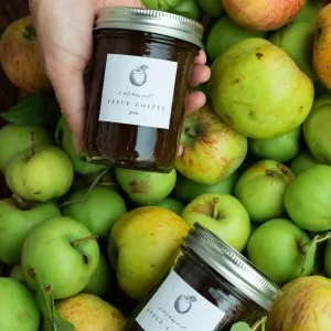 Apple preserves in mason jar in front of basket of apples