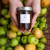 Apple preserves in mason jar in front of basket of apples