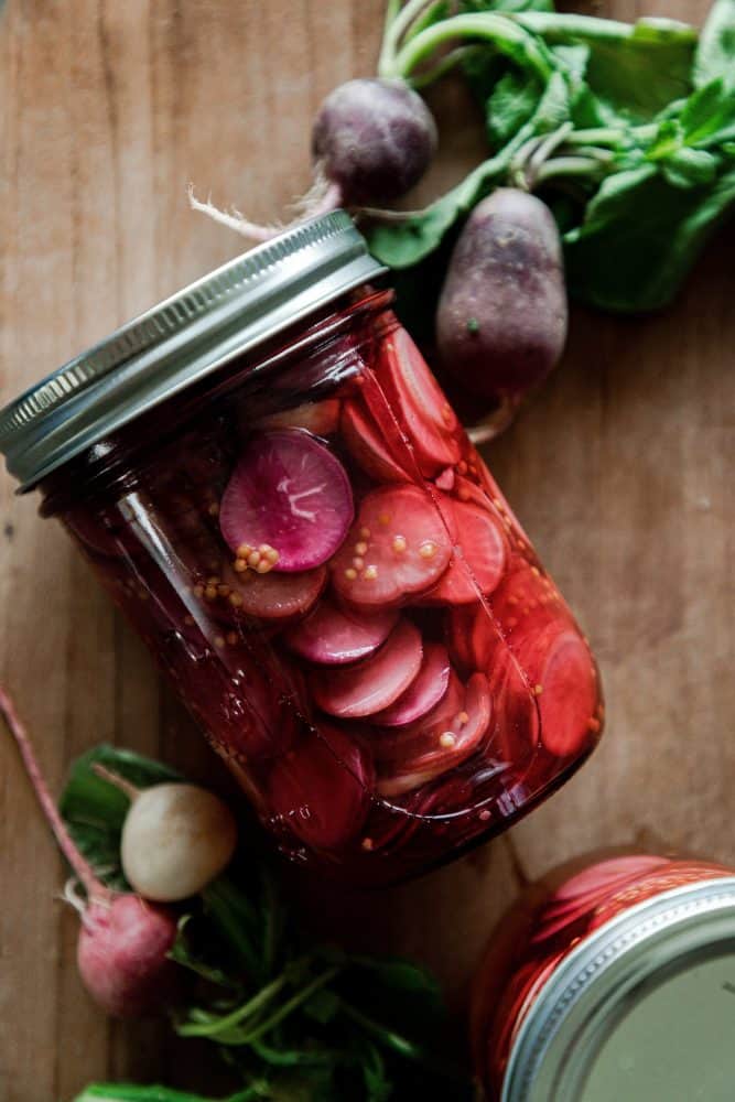 Jar of pickled radishes on table