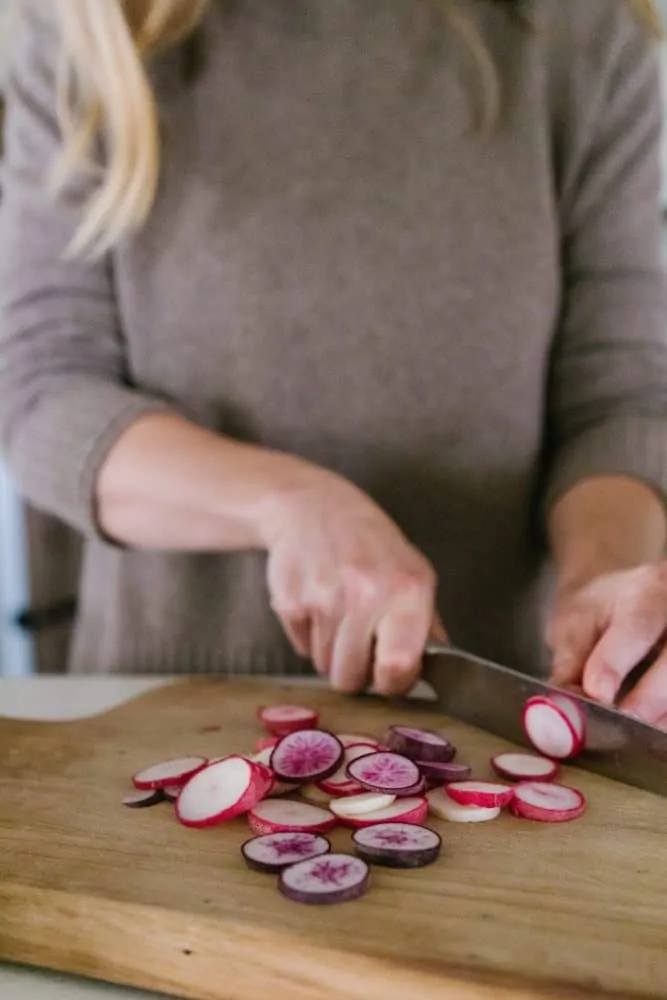Girl cutting radishes in farmhouse kitchen