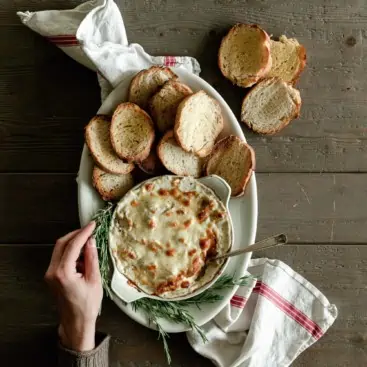 platter of cheesy artichoke dip with bread