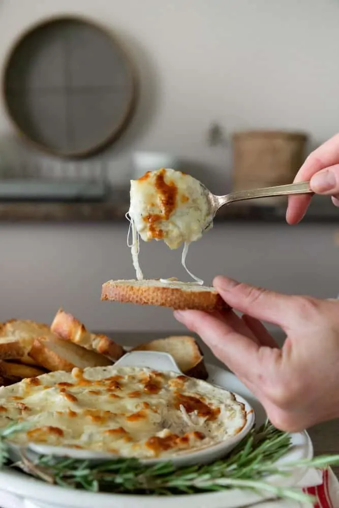 platter of cheesy artichoke dip on bread