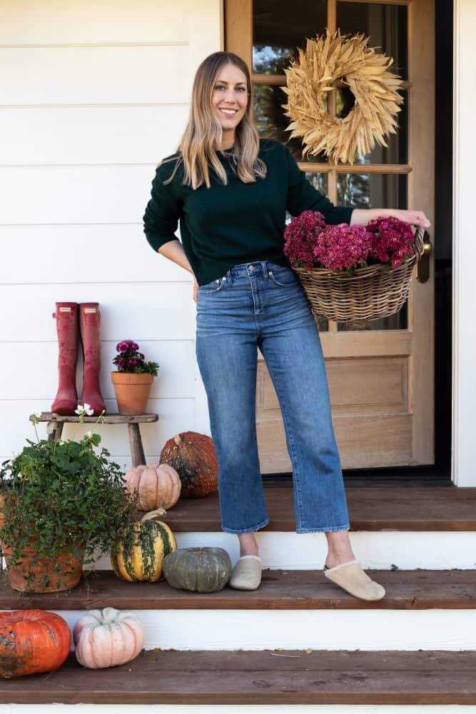 Girl holding basket of pink mums on fall porch