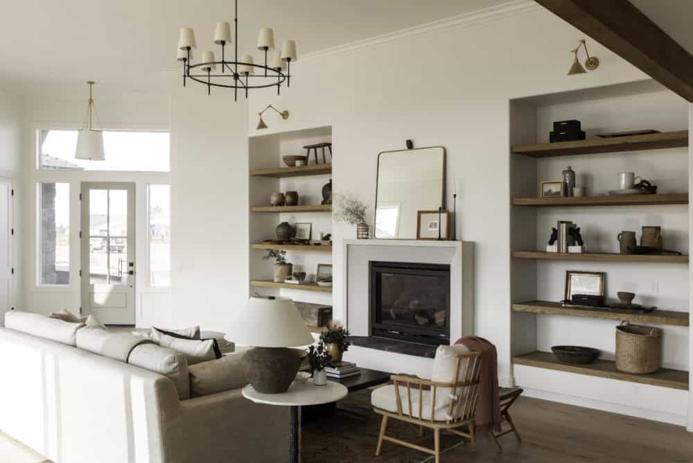 Swiss coffee living room with cement fireplace surround and floating wood open shelves with blue door. 