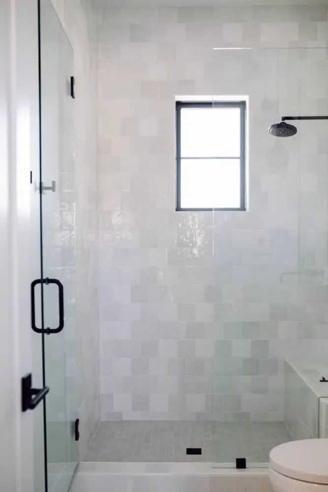 Shower with white Cloe tile and black hardware with grey accents.