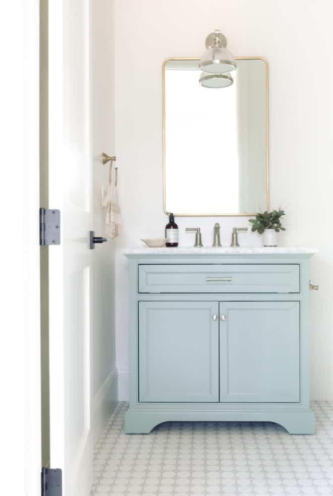 Beautiful small bathroom design with blue vanity and white walls with mixed metals.