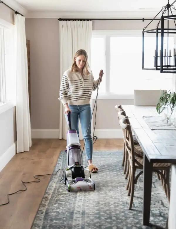 Girl using BISSELL carpet cleaner in dining room.