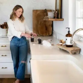 Woman standing in kitchen making DIY coconut coffee scrub with Ball home canning products mason jars.