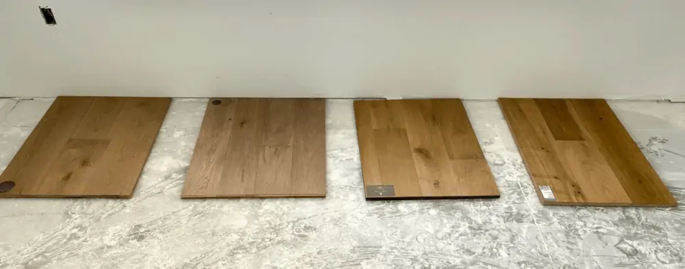 Four samples of engineered hardwood floors laid on a concrete slab for consideration.
