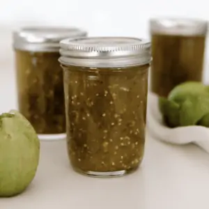 Three jars of tomatillo salsa in canning jars on countertop.