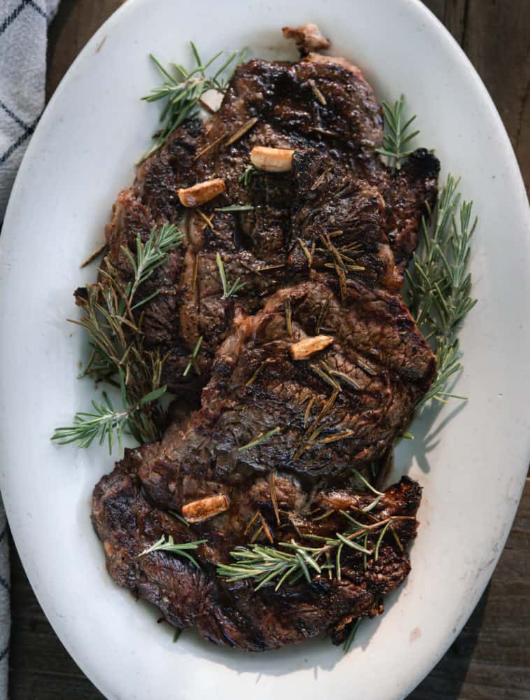 Platter of 2 grilled ribeye steaks with browned butter, garlic, and rosemary!