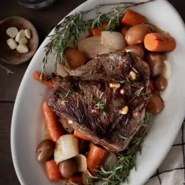 Rump Roast plated with roasted carrots, onions and potatoes.