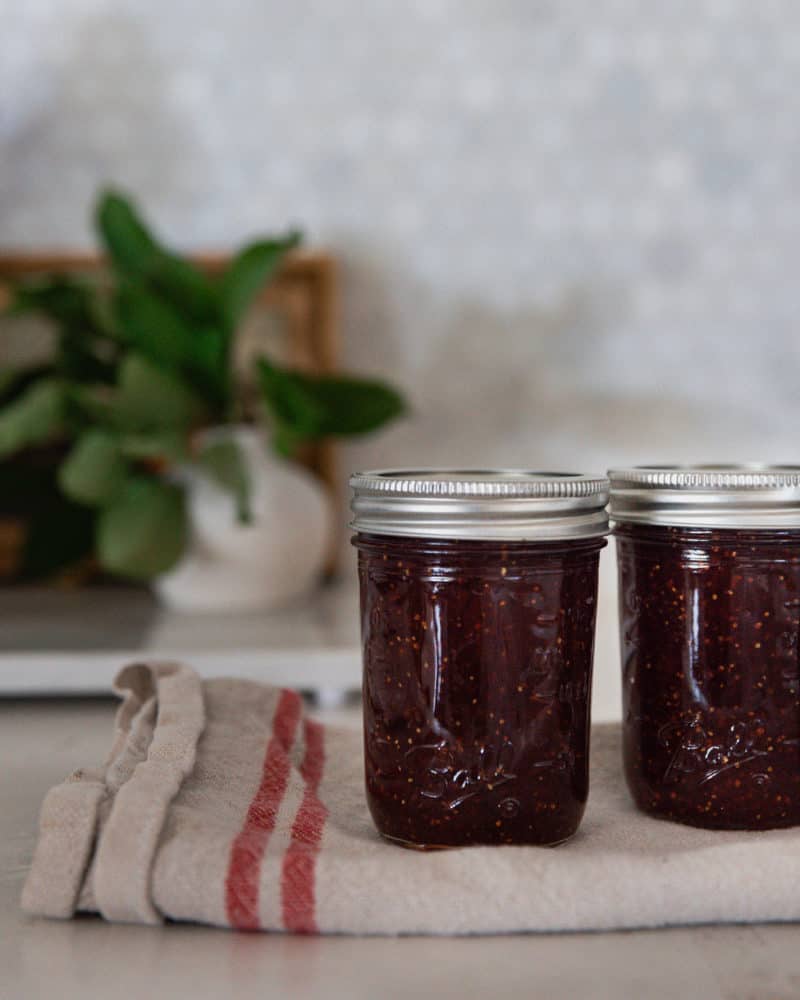 Two mason jars filled with fig jam on a towel.