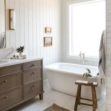 Bathroom painted with Classic Gray by Benjamin Moore with shiplap and beautiful oversized white tub and white oak vanity.