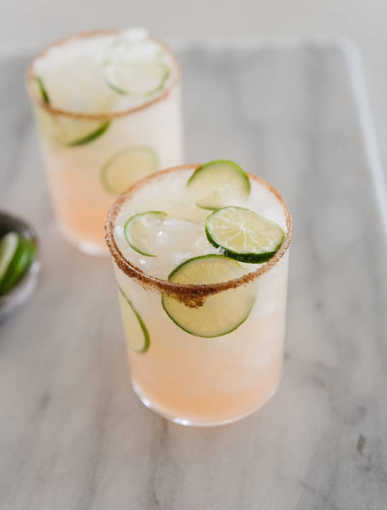 Paloma drink with limes on a marble cutting board