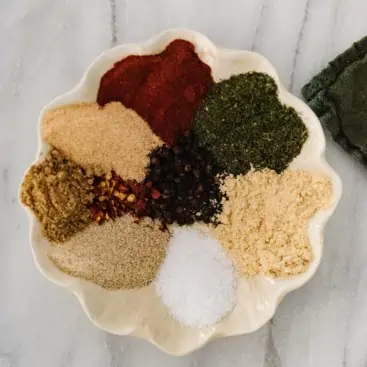 arrangement of spices for steak seasoning in a scalloped edge dish