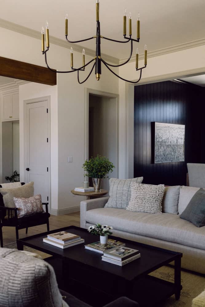 living room scene showing a corner of a sofa, side chair and decor with a black painted wall in the background