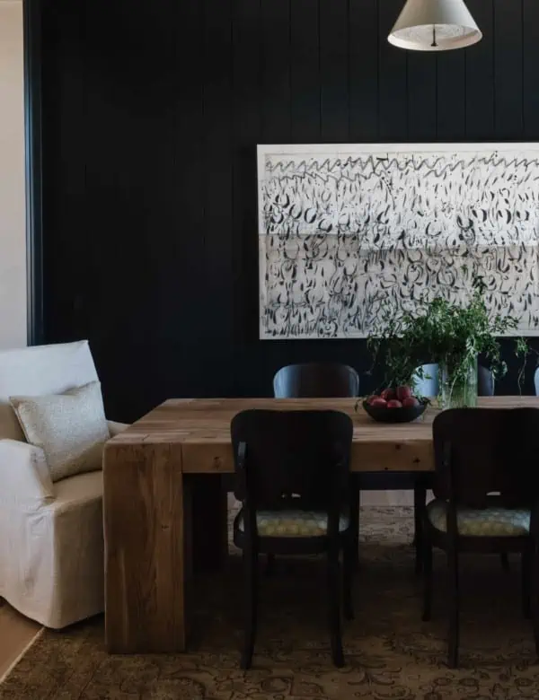dining room with large abstract artwork on a black wall with the table and chairs in the foreground