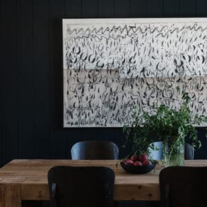 dining room with large abstract artwork on a black wall with the table and chairs in the foreground