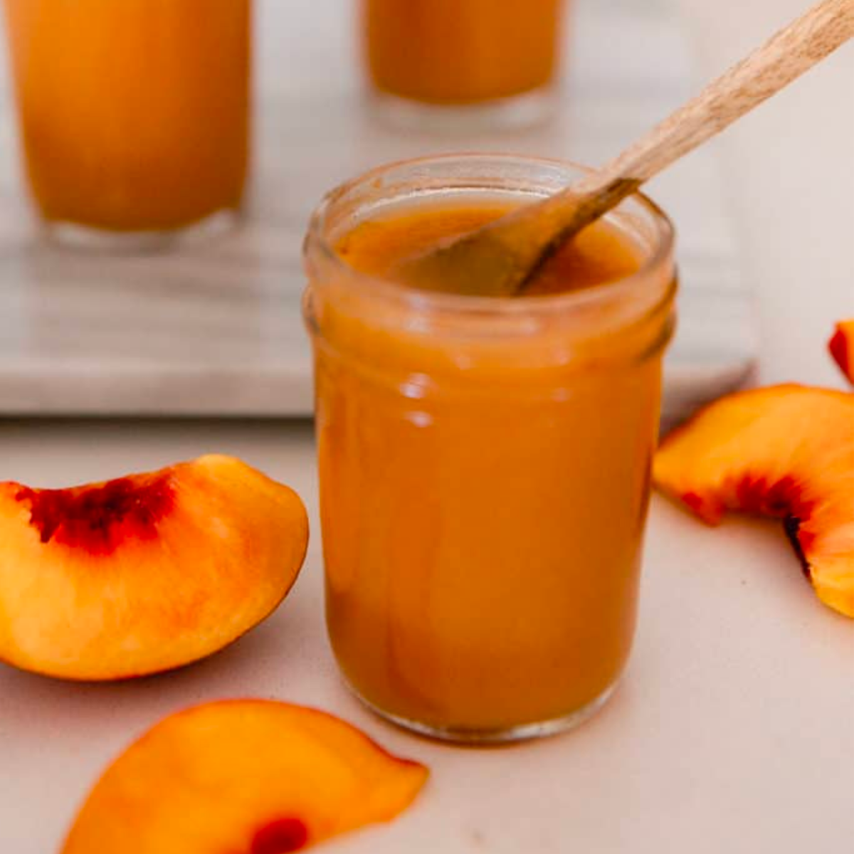 peach ginger butter in glass mason jar with fresh peach slices on counter