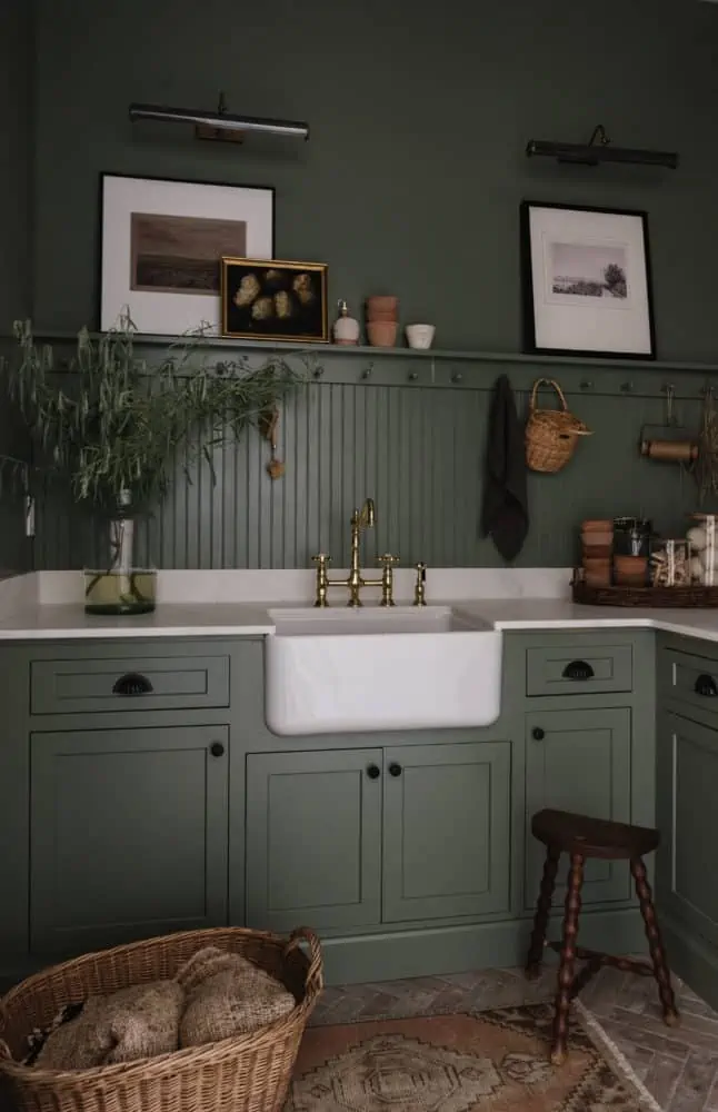 green cabinets and walls with a peg rail and marble counters with white farmhouse sink