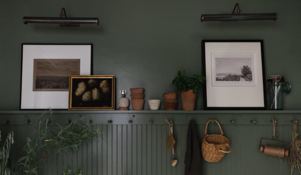 green cabinets and walls with a peg rail and marble counters with white farmhouse sink