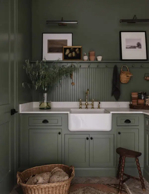 green cabinets and walls with a peg rail and marble counters with white farmhouse sink