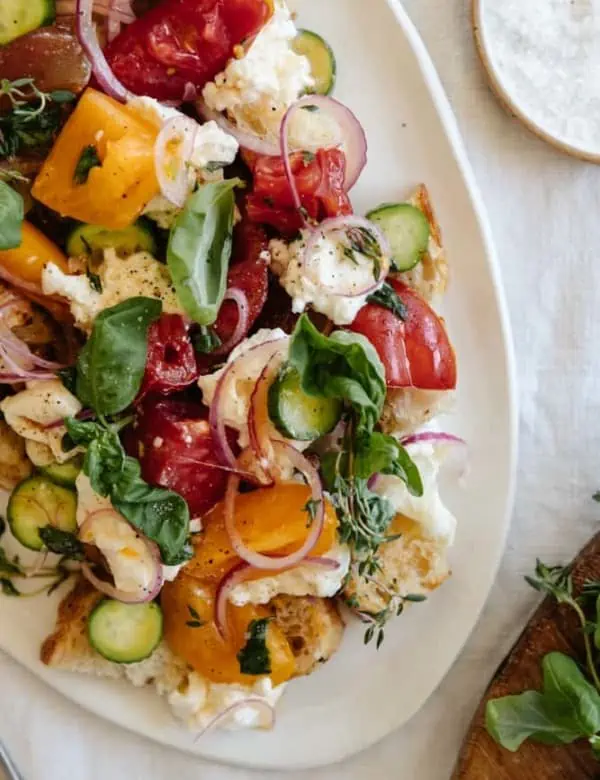 panzanella salad on a white platter on a linen tablecloth