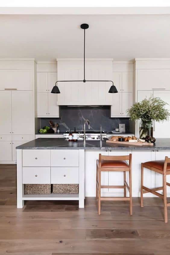 white kitchen with dark grey and white veined granite countertops with a black pendant light above the island