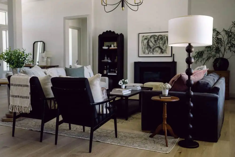 side view into a living room with 2 sofas facing each other, greenery on side tables, and a large chandelier in the center of the room