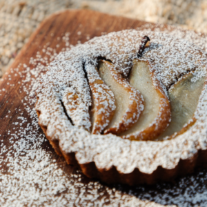 close up of powder sugar coated pear tart on a wood cutting board