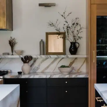 kitchen with bold marble countertop and backsplash created into a small shelf with art and decor on the shelf and countertop
