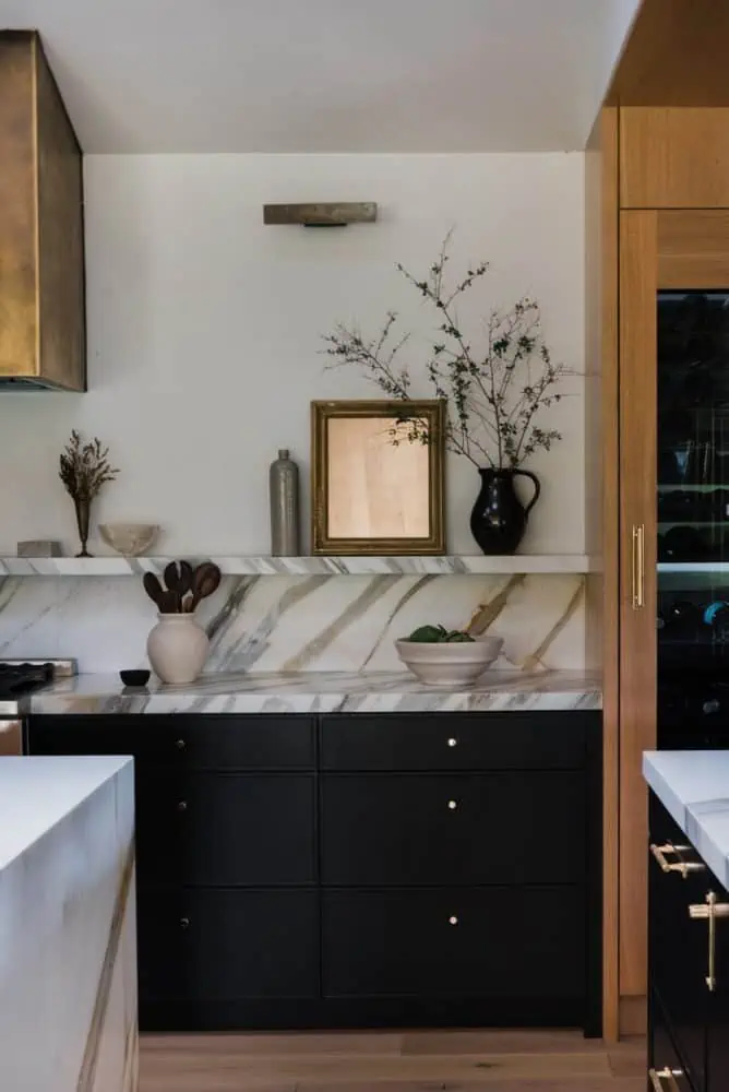 kitchen with bold marble countertop and backsplash created into a small shelf with art and decor on the shelf and countertop